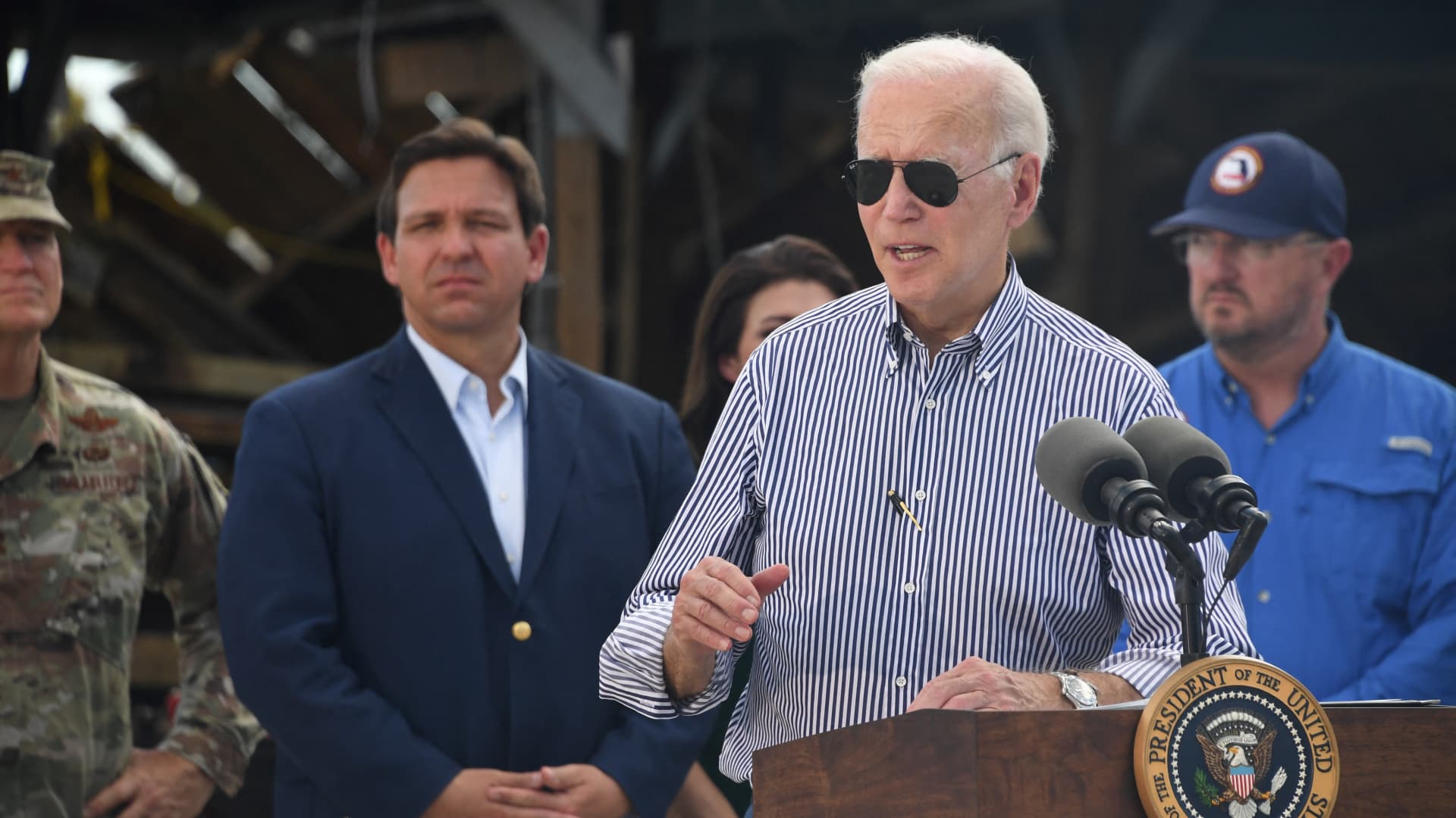 US President Joe Biden speaks in a neighborhood impacted by Hurricane Ian at Fishermans Pass in Fort Myers, Florida, on October 5, 2022 as Florida Governor Ron DeSantis looks on.