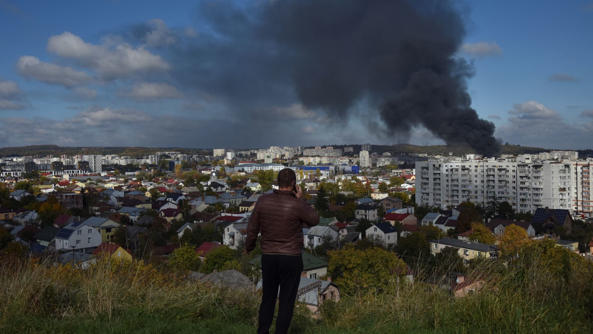 A man looks as smoke rises over the city after Russian missile strikes, amid Russia's attack on Ukraine, in Lviv, Ukraine October 10, 2022.