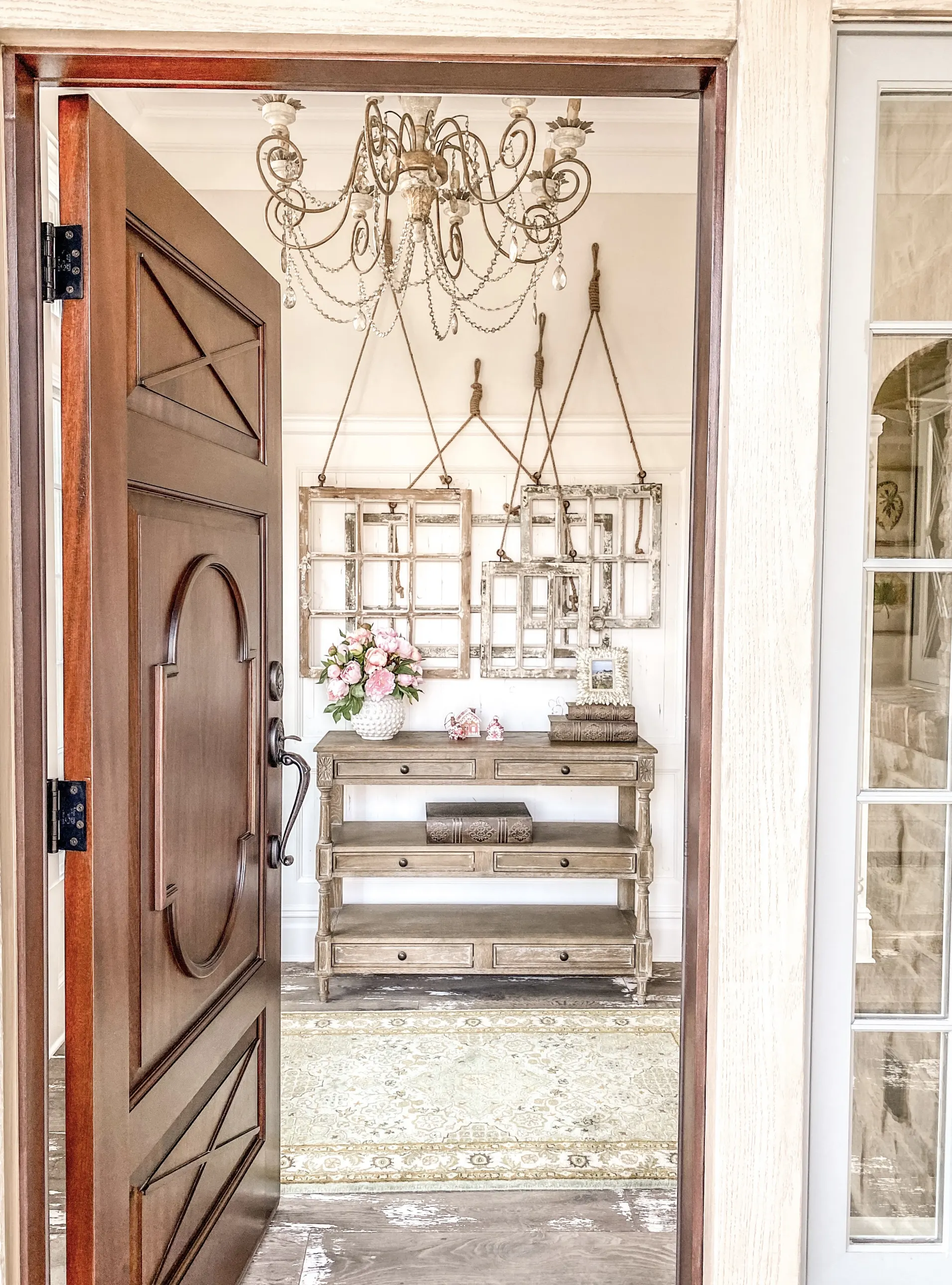 The entrance to the home is styled with a carved door and an elegant chandelier. 