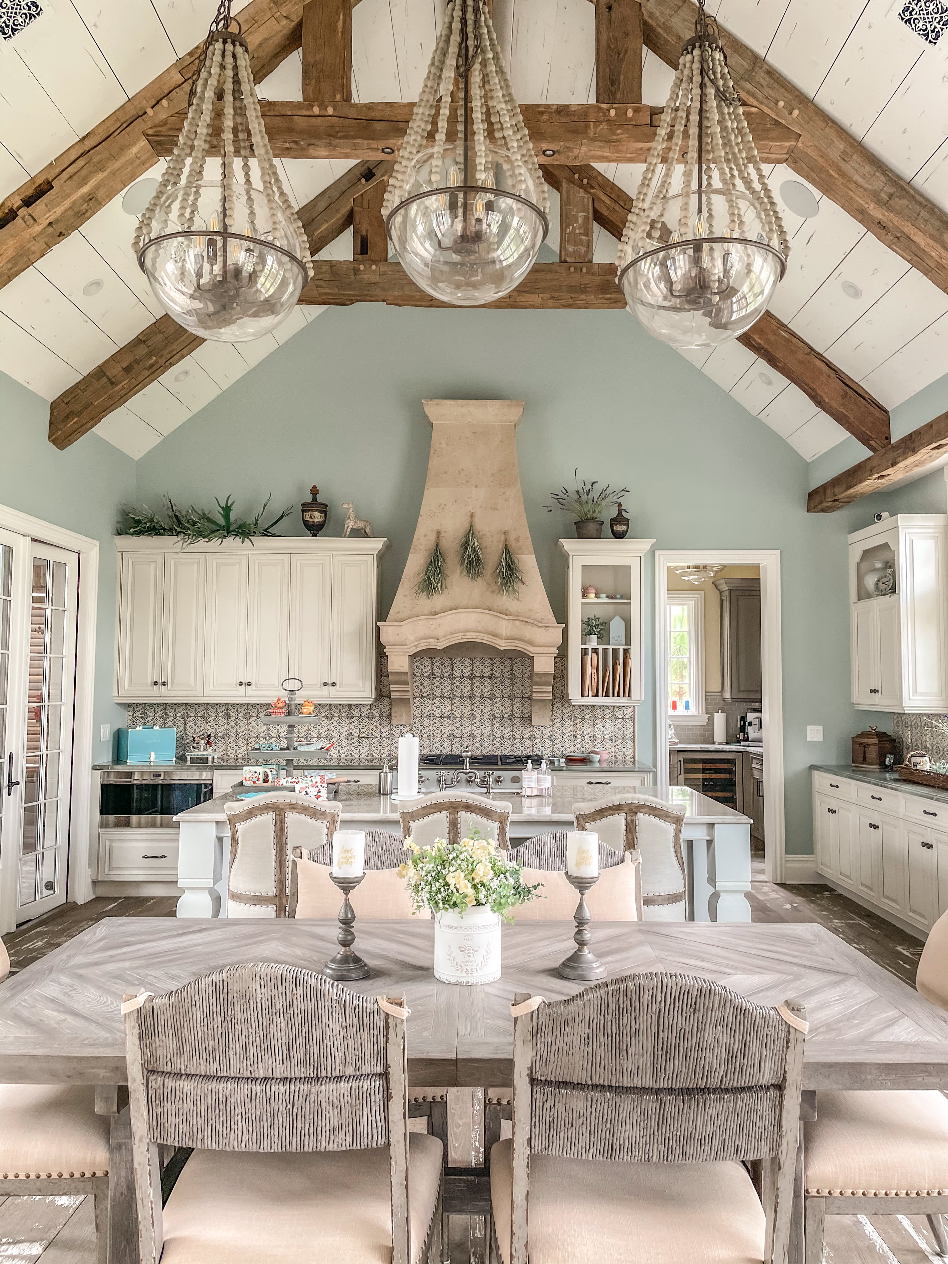 Distressed wooden details, intricate tiles and a towering kitchen hood give the space a French-countryside feel.