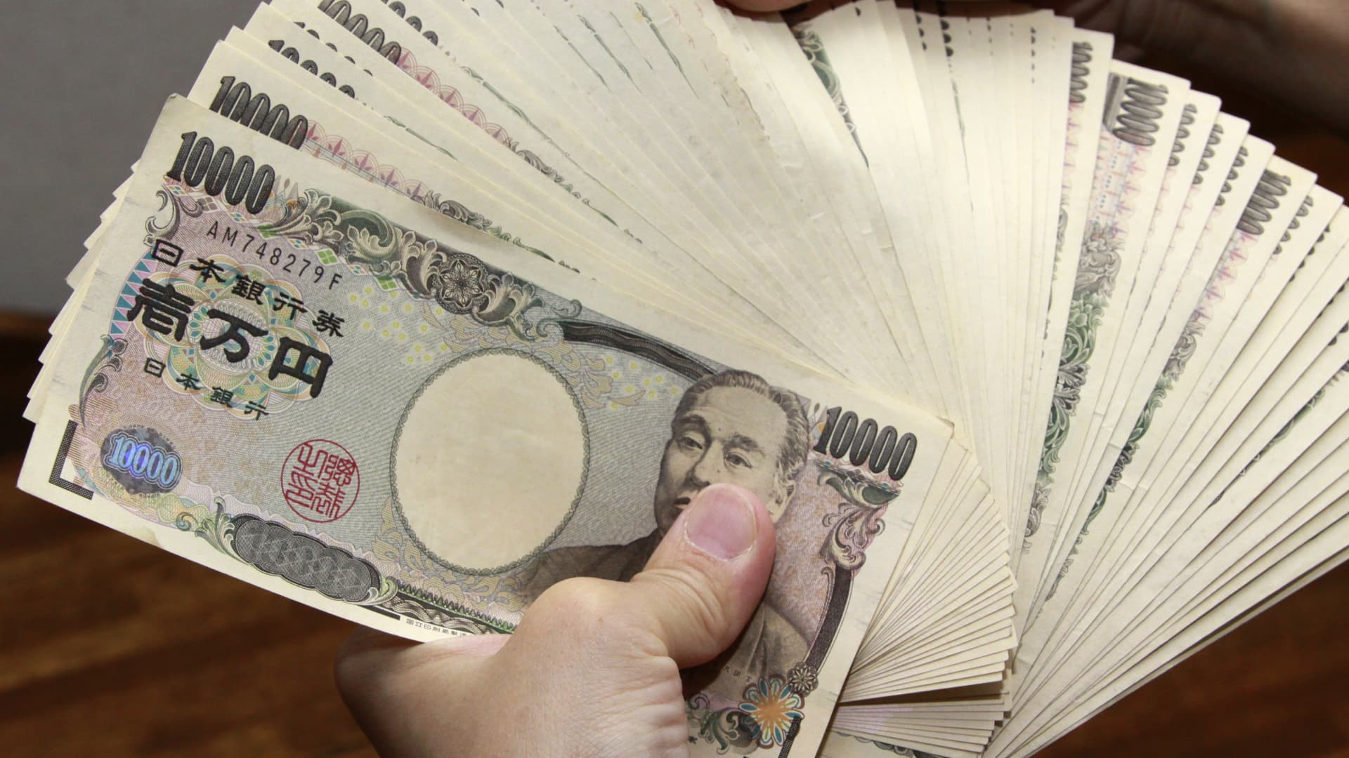 A bank teller counts 10,000 yen, or 118 USD, bank notes in Tokyo.