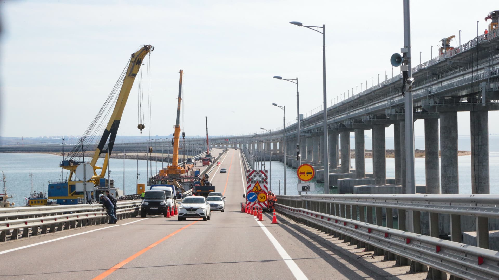 This picture taken on October 13, 2022 shows workers restoring damaged parts of the Kerch Bridge that links Crimea to Russia, which was hit by a blast on October 8, 2022.