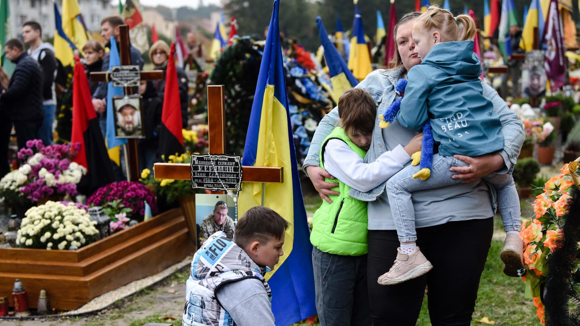 People react as they visit the graves of fallen Ukrainian soldiers at Lychakiv Cemetery in Lviv, to mark Ukraine's Defenders Day on October 14, 2022.