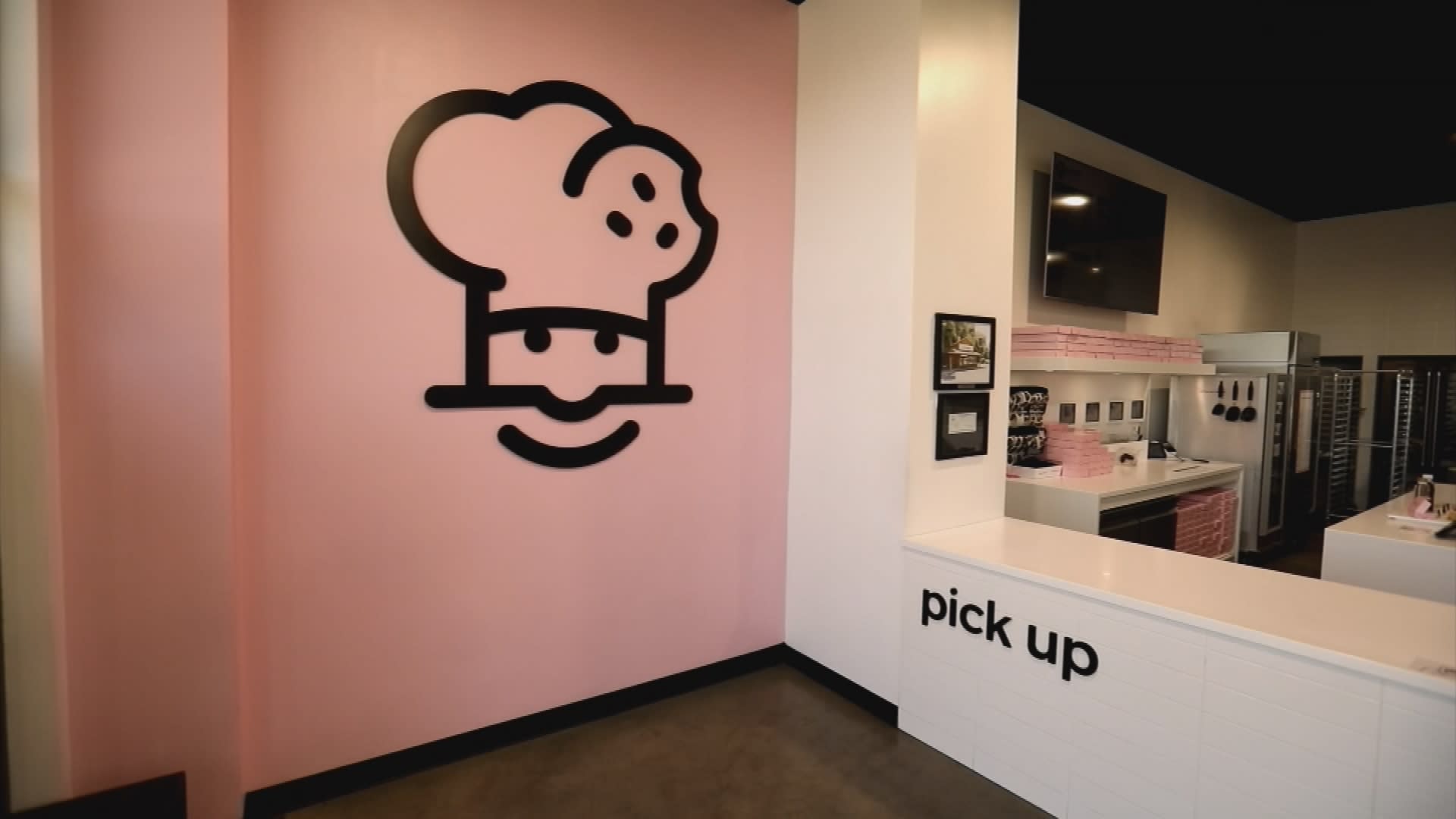Interior of a Crumbl cookie store with company's logo on the wall.