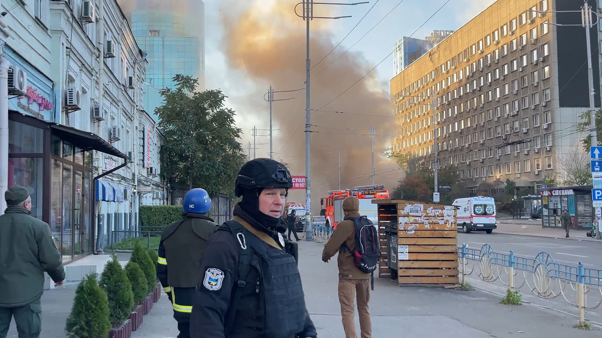 This frame grab from AFPTV video footage shows smoke rising past first responders in Kyiv on Oct. 17, 2022.