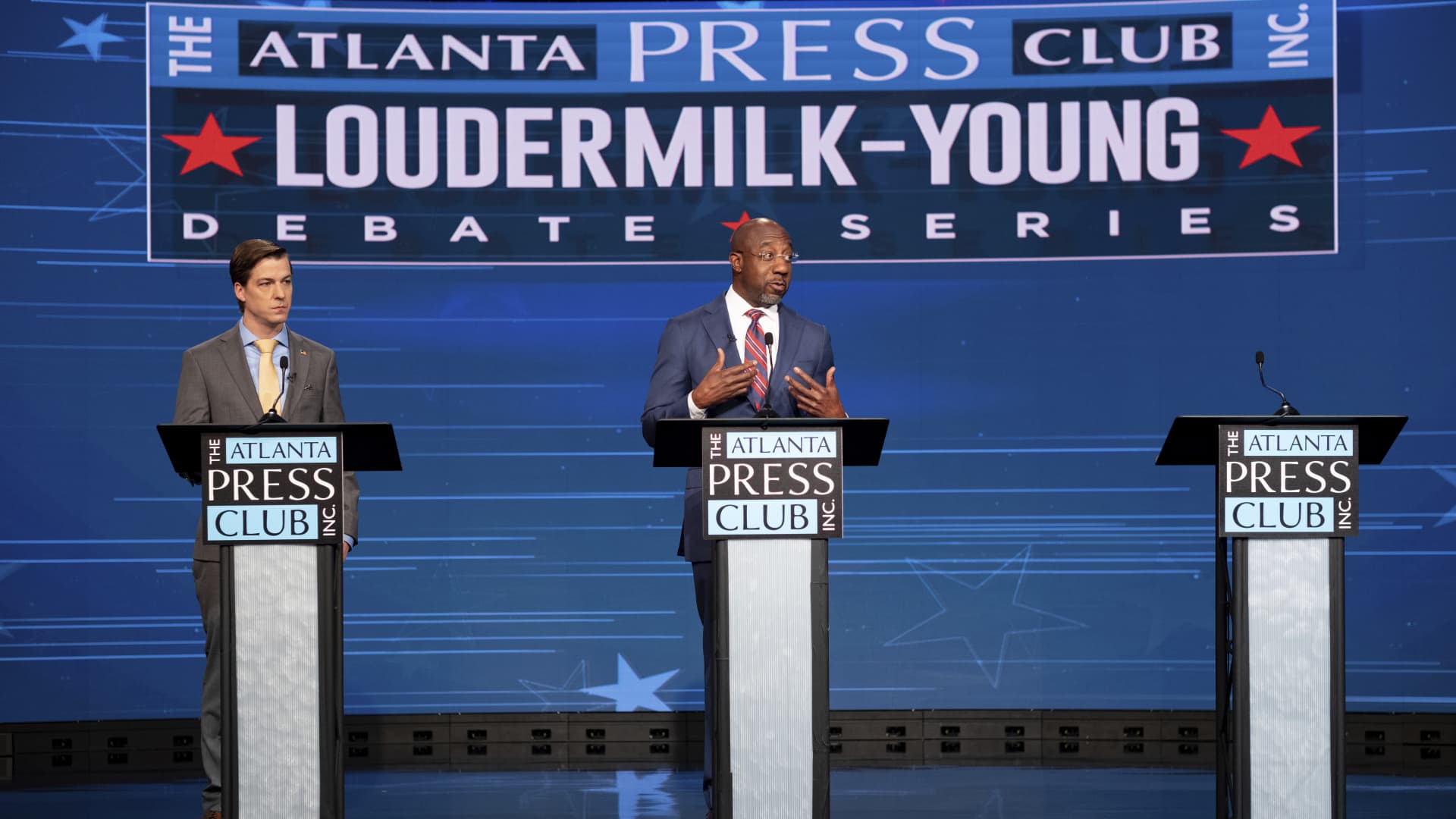 Libertarian challenger Chase Oliver, left, and Sen. Raphael Warnock, D-Ga., participate in a U.S. Senate debate during the Atlanta Press Club Loudermilk-Young Debate Series in Atlanta on Sunday, Oct. 16, 2022. The empty podium at right was for Republican challenger Herschel Walker, who was invited but did not attend.