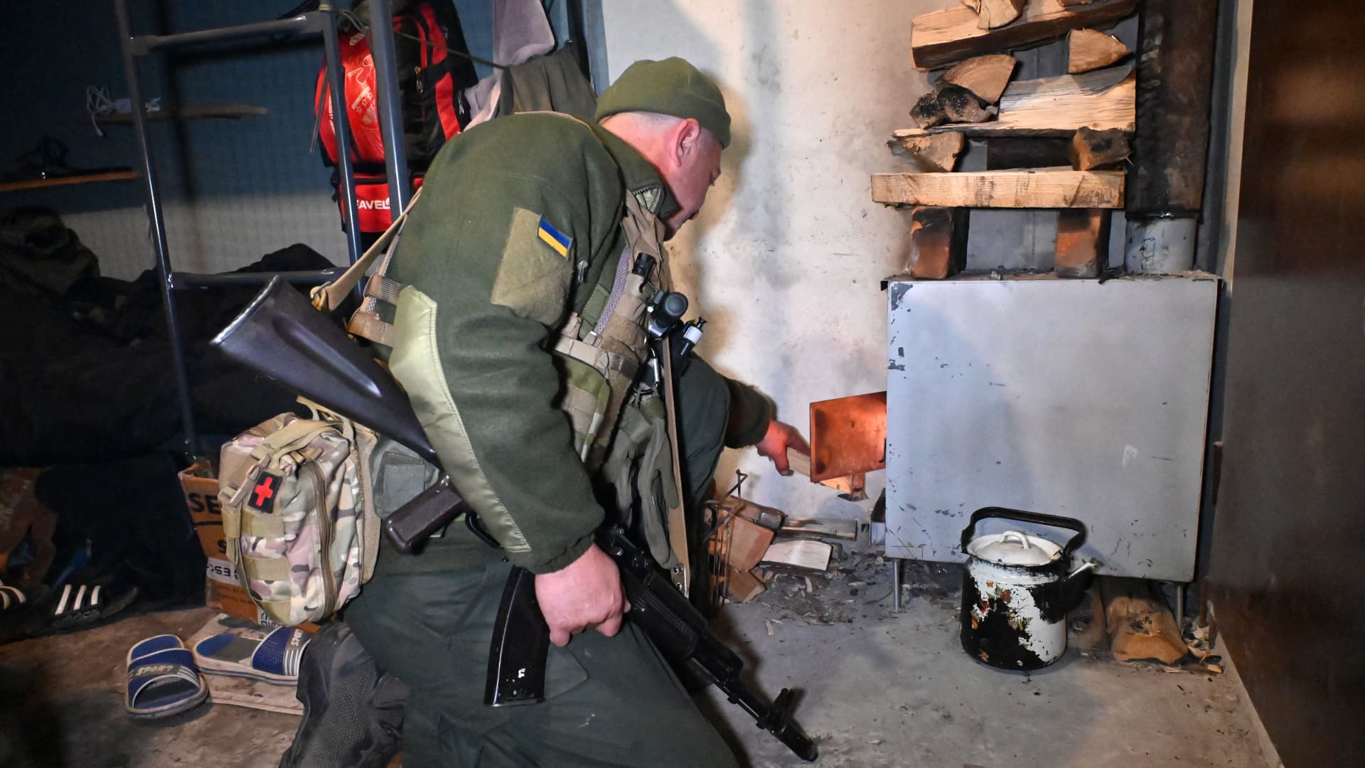 A soldier of the National Guard of Ukraine provides a stove with firewood in a dugout in the northern occupied territories of Kharkiv region on October 21, 2022, amid the Russian military invasion of Ukraine.