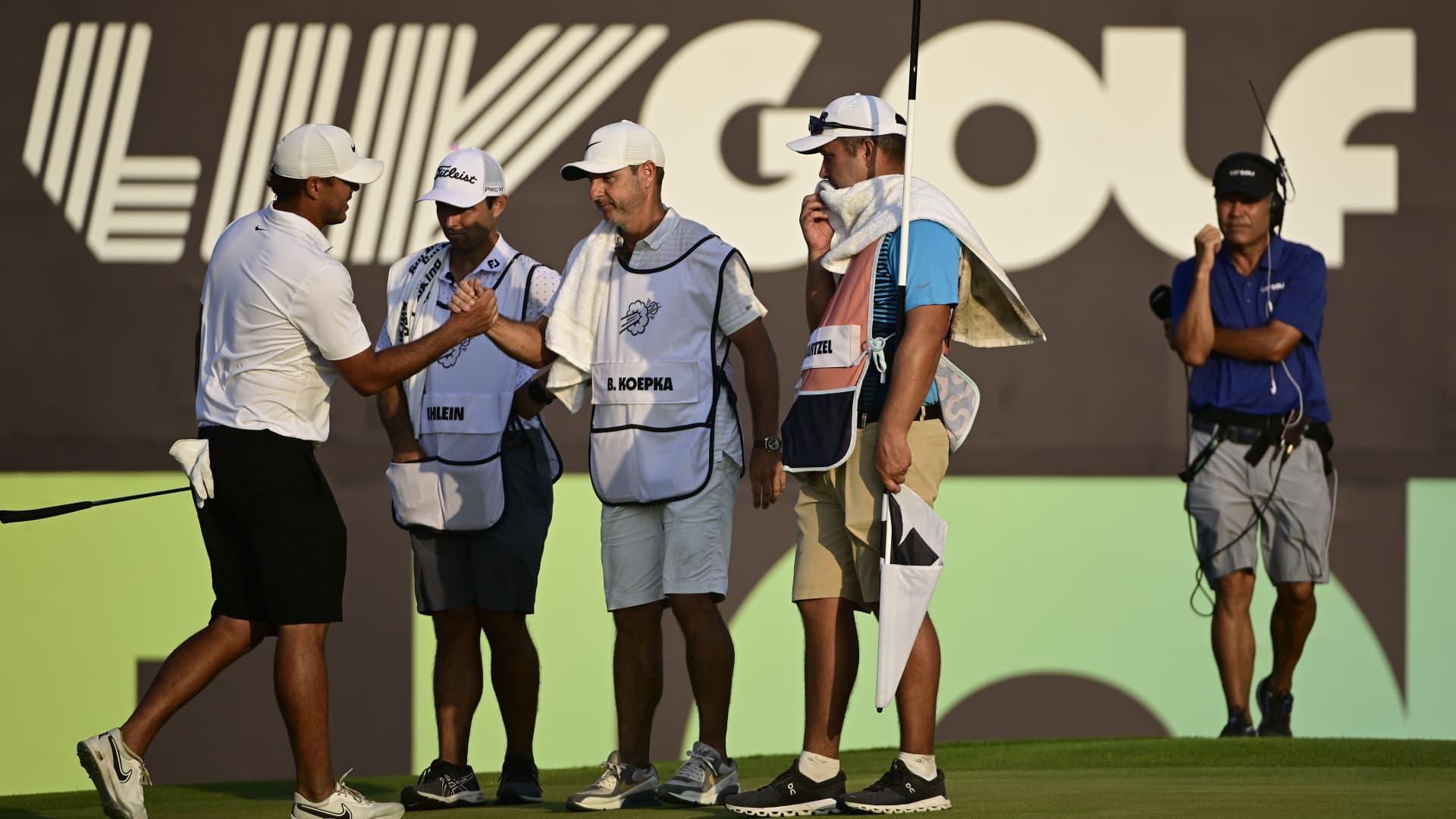 Team Captain Brooks Koepka of Smash GC and caddie Ricky Elliott shake hands on the 18th green during day three of the LIV Golf Invitational - Jeddah at Royal Greens Golf & Country Club on October 16, 2022 in King Abdullah Economic City, Saudi Arabia.