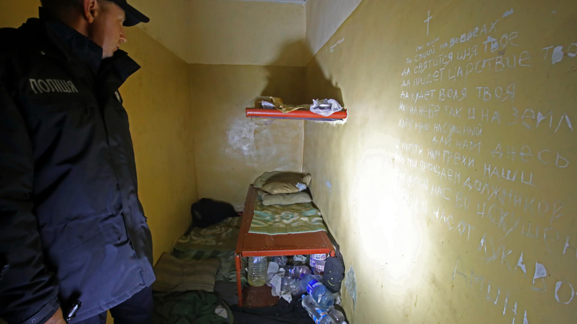 A Ukrainian police officer examines a cell as the words of the Lord's Prayer are written on the wall at the District Police Department used by Russian occupiers for torture, Balakliia, Kharkiv Region, northeastern Ukraine.