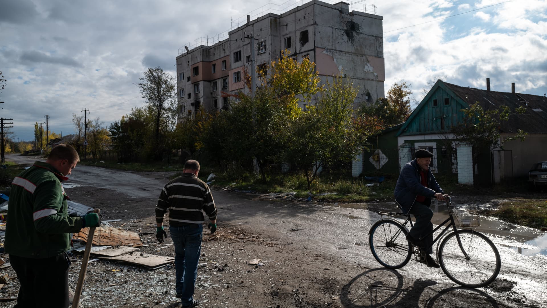 Workers clean debris off of the street in front of a destroyed storage complex in the recently recaptured village of Archangelske in Kherson, Ukraine on 26 Oct. 2022.