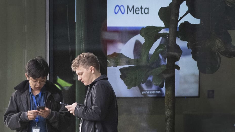 Personas que usan sus teléfonos móviles fuera de las oficinas de Meta, la empresa matriz de Facebook e Instagram, en King's Cross, Londres.