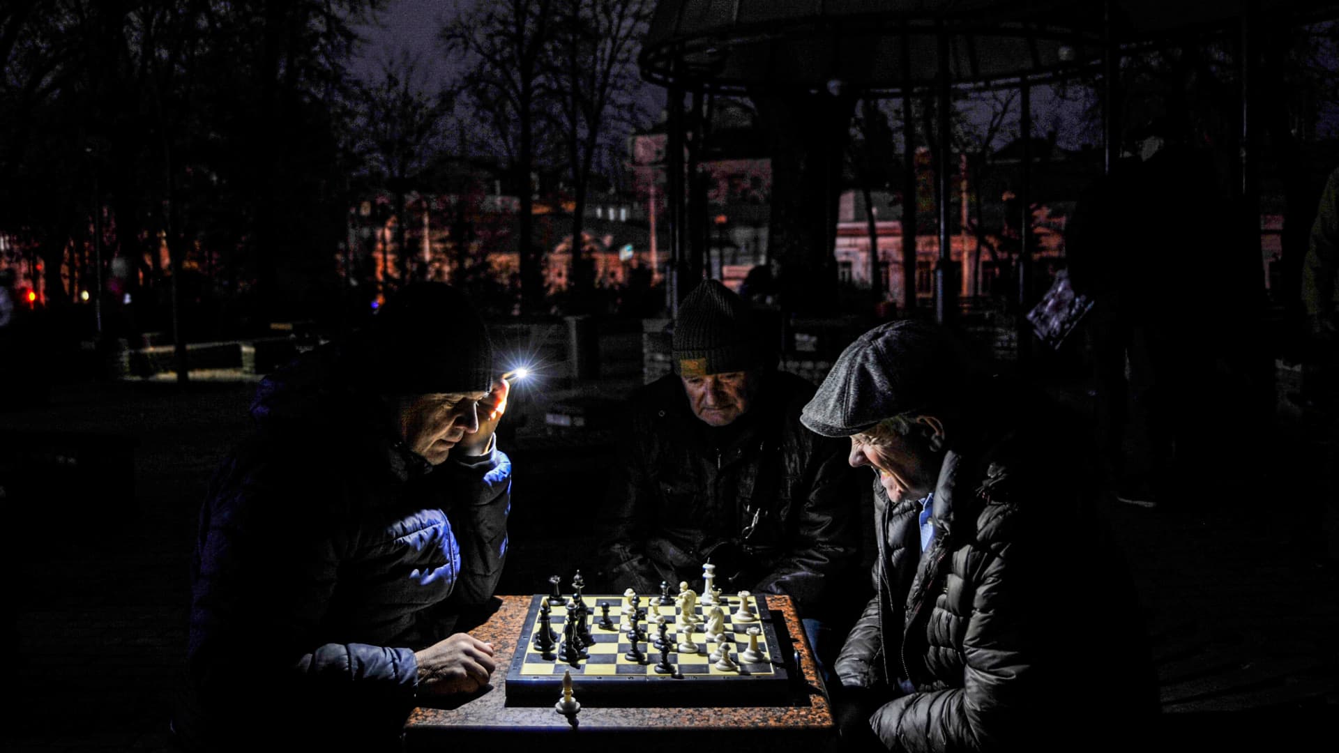 Men play chess by a flashlight in a park in Kyiv during a power cut.