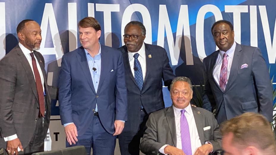 Ford CEO Jim Farley (center left) on stage with the Rev. Jesse Jackson (seated) and other officials on Nov. 15, 2022 at an automotive conference hosted by the Rainbow Push Coalition in Detroit.
