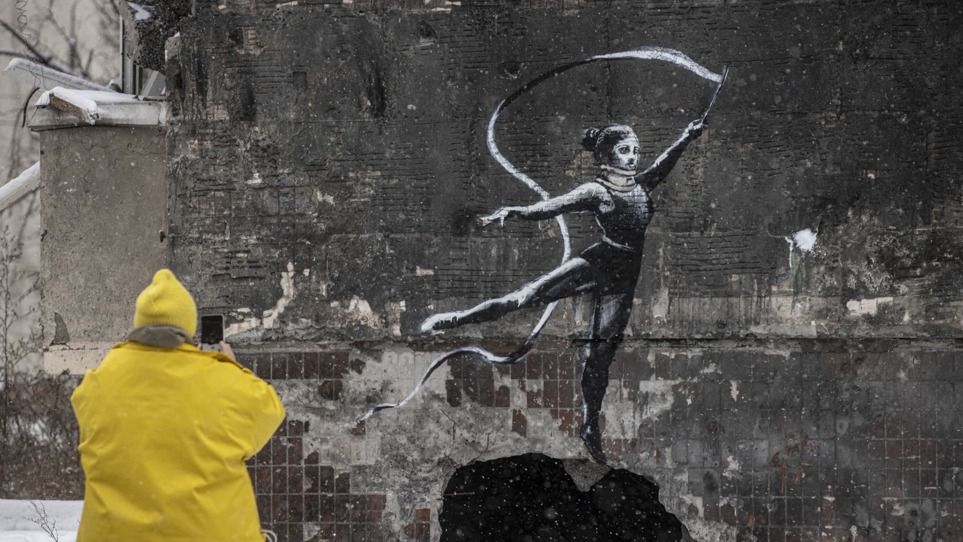 A person takes a photo of graffiti created by England-based street artist, Banksy, in Irpin located Kyiv district, Ukraine on November 19, 2022.