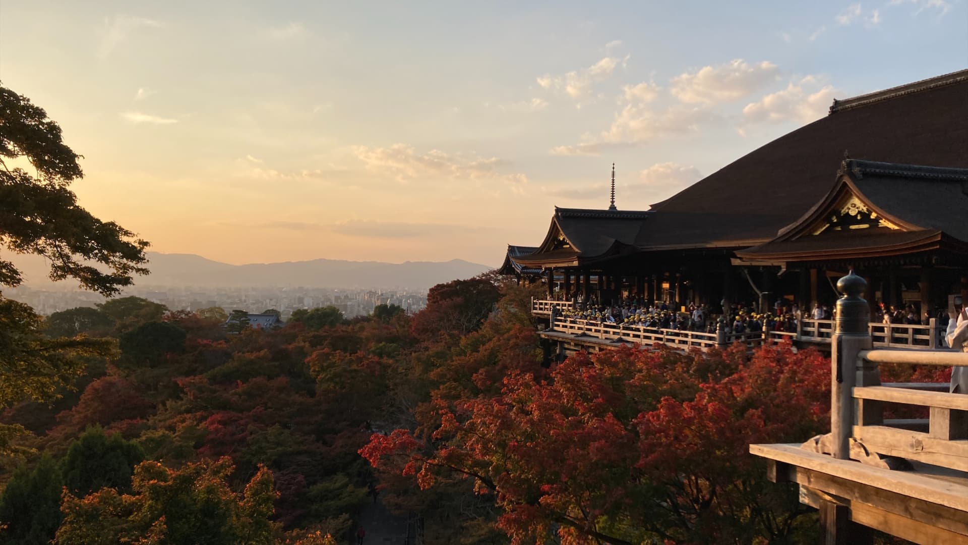 Visitors gather on a terrace near the Kiyomizu-dera to watch the sunset and autumn leaves in Kyoto, Japan.