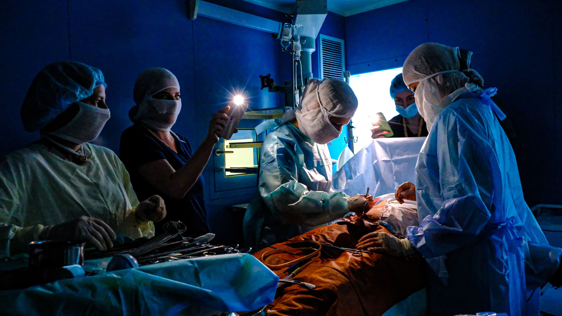 Doctors operate with phone flashlights after power outages due to conflicts within the Russian-Ukrainian war in Kyiv, Ukraine on November 30, 2022. 