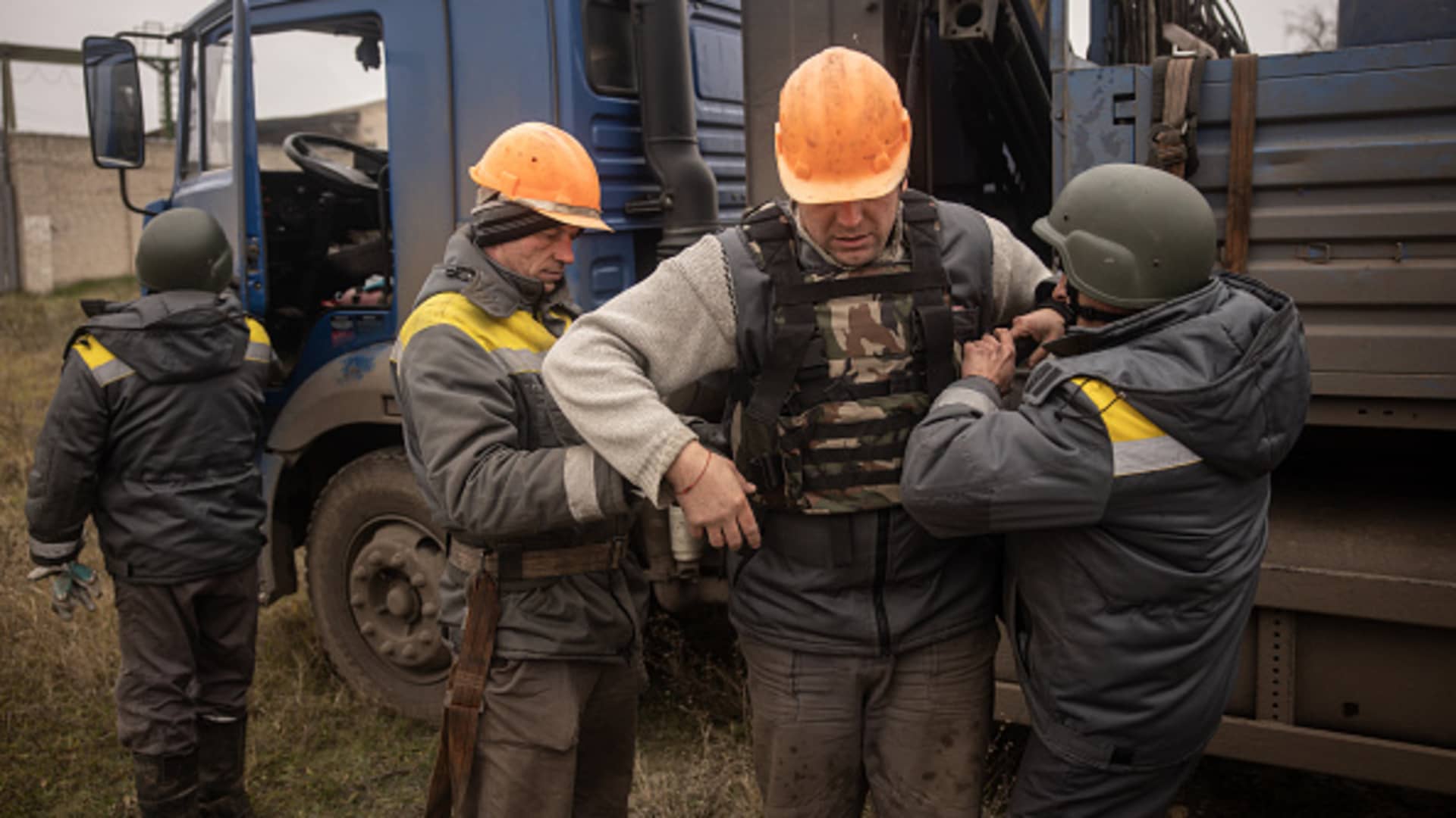 Electricity workers from a team brought in from Odessa put on bullet proof vests and helmets before starting work fix a destroyed high voltage power line on December 01, 2022 in Kherson, Ukraine.