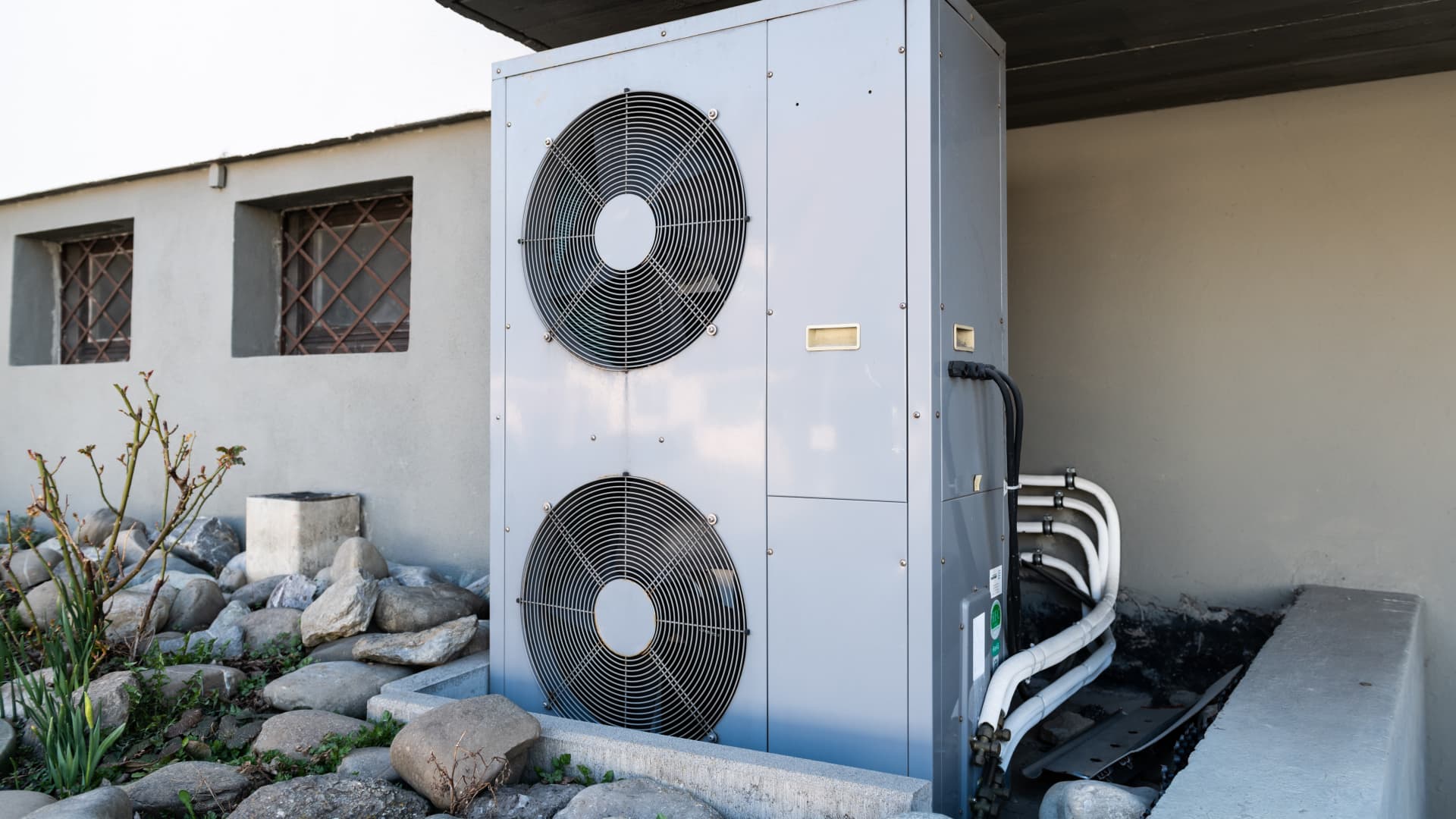 The ventilation system of a geothermal heat pump located in front of a residential building.