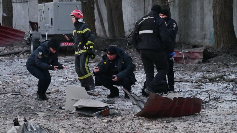Rescuers and police experts examine the remains of a drone following a strike on an administrative building in Kyiv on Dec. 14, 2022.