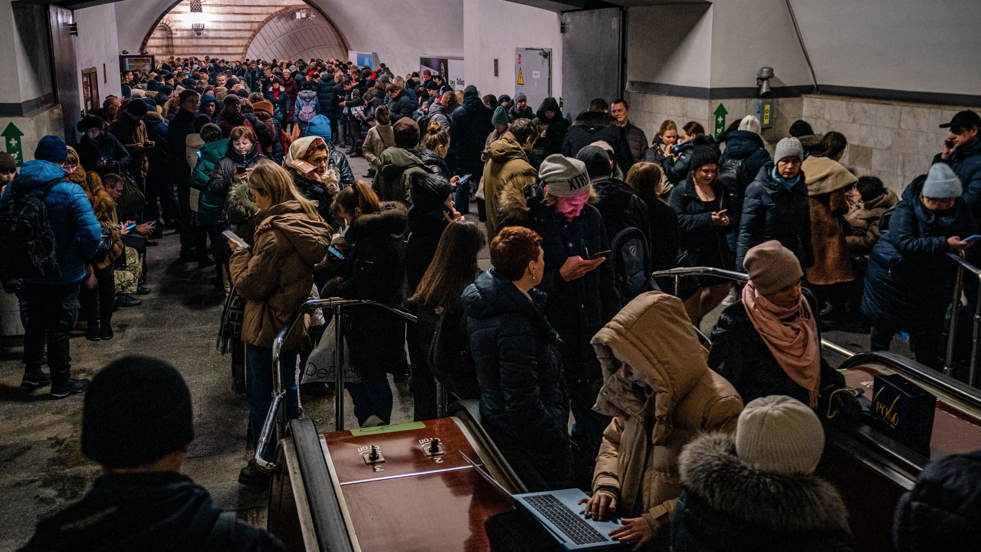 Civilians sit on an escalator while take shelter inside a metro station during an air raid alert in the centre of Kyiv on December 16, 2022, amid the Russian invasion of Ukraine.