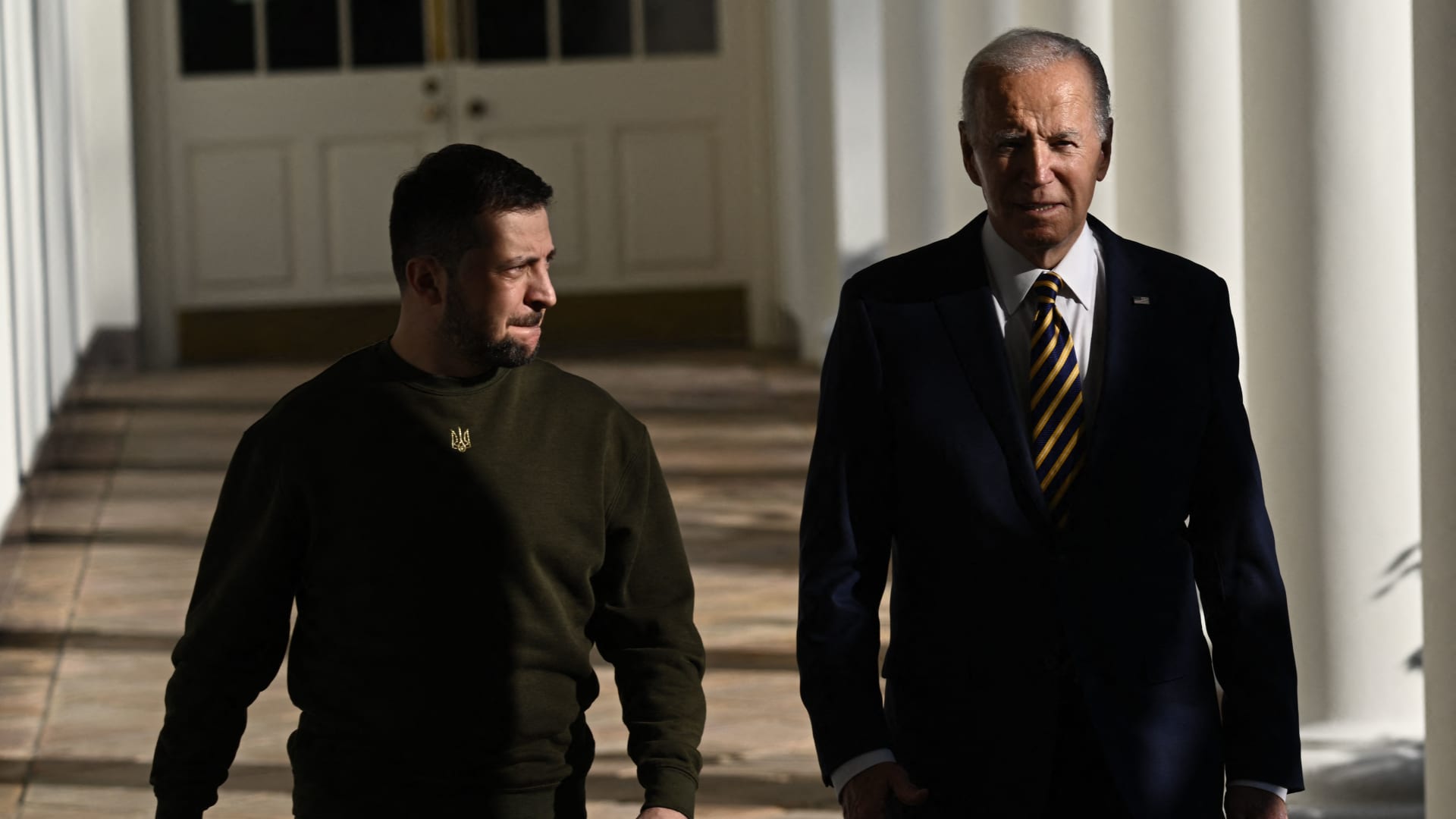 US President Joe Biden walks with Ukraine's President Volodymyr Zelenskyy through the colonnade of the White House, in Washington, DC on December 21, 2022.