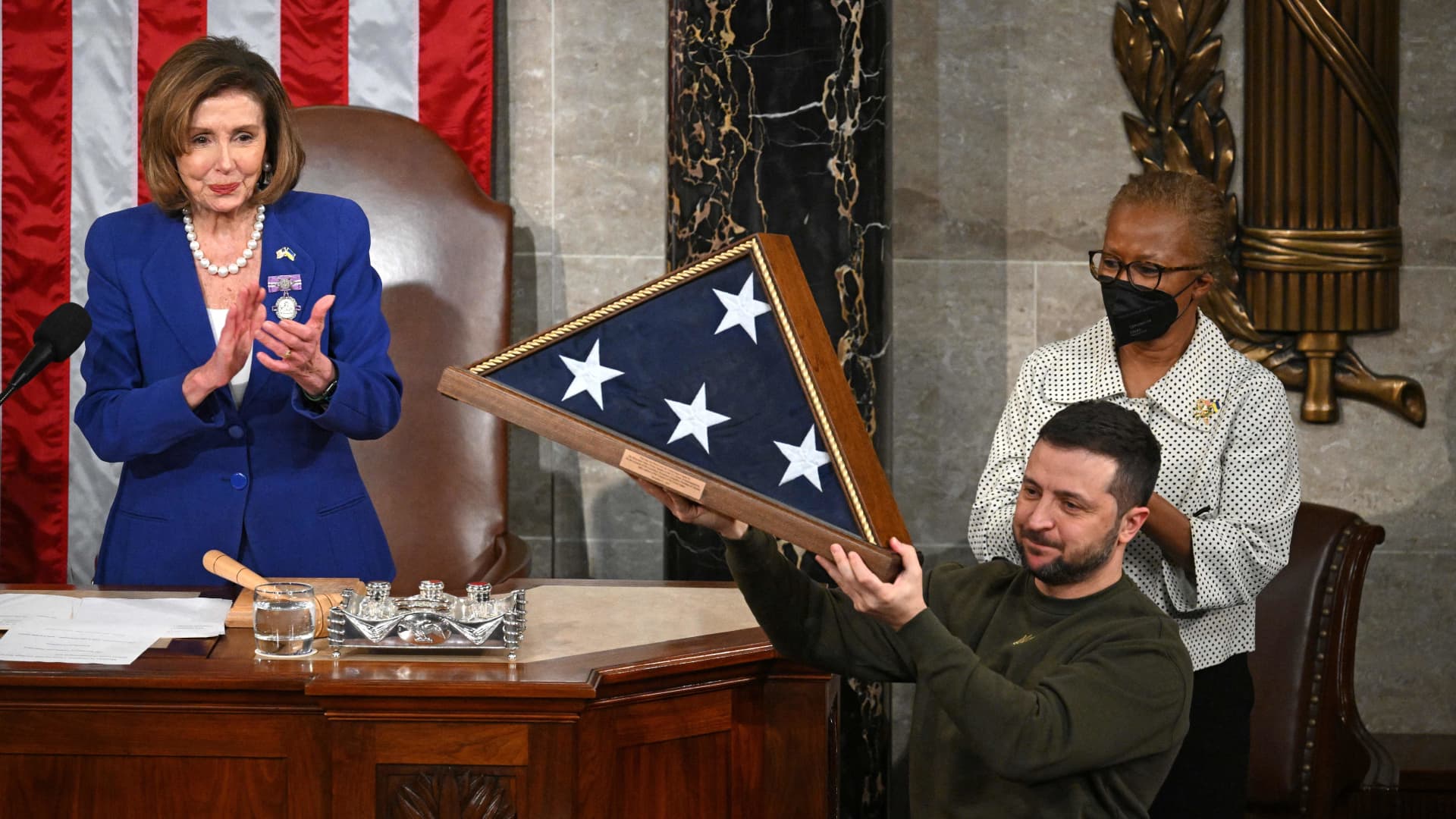Ukraine's President Volodymyr Zelensky receives from US House Speaker Nancy Pelosi (D-CA) (L) a US national flag during his address to the US Congress at the US Capitol in Washington, DC on December 21, 2022.