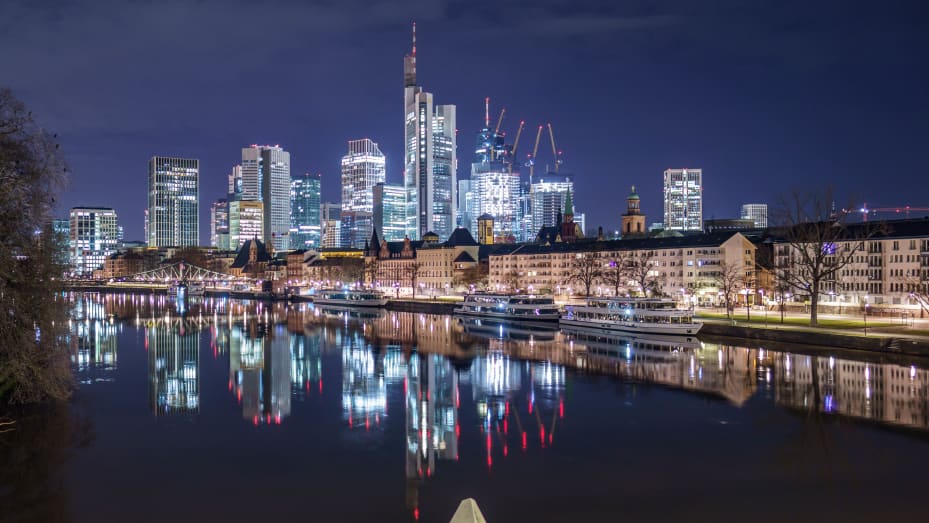 Antes del amanecer, los edificios residenciales y las torres de oficinas de la metrópolis bancaria de Frankfurt se reflejan en el tranquilo río Meno.
