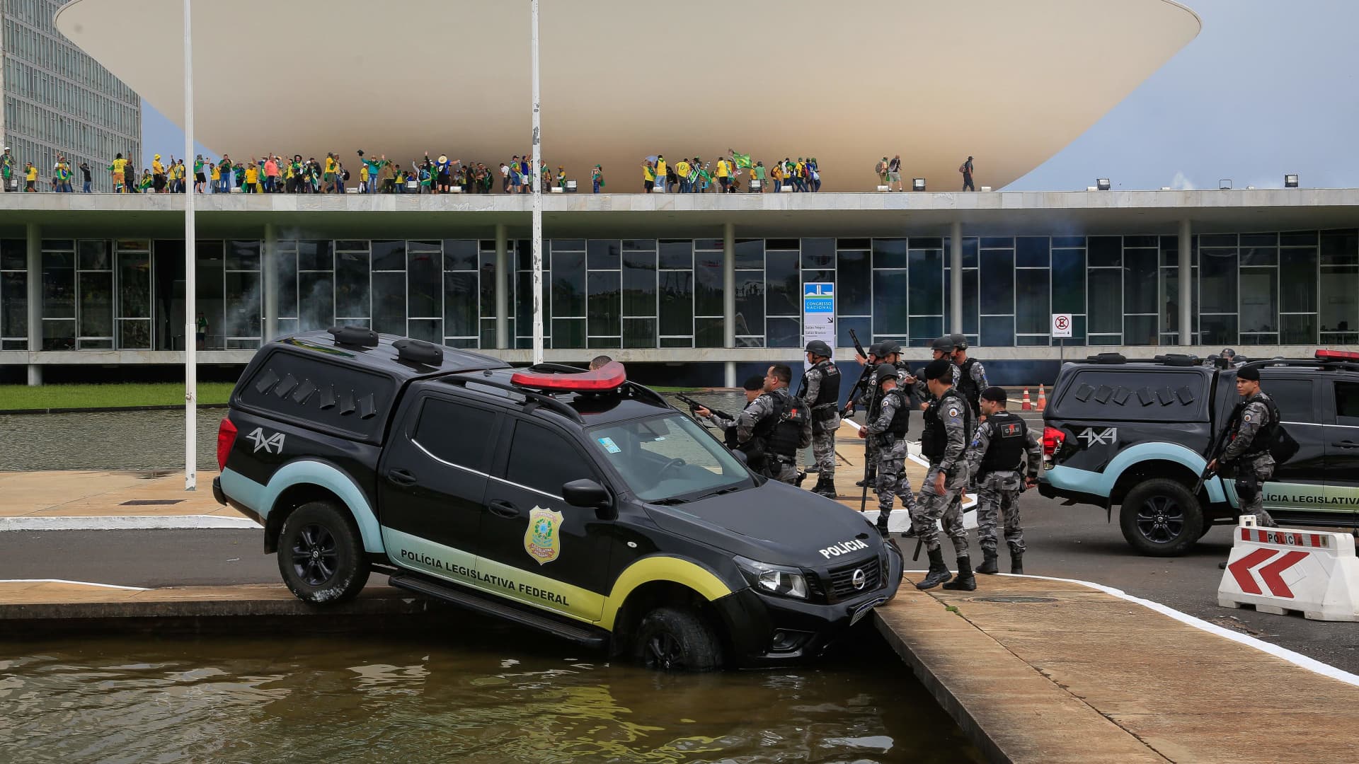 Members of the Federal Legislative Police stand next a vehicle that crashed into a fountain as supporters of Brazilian former President Jair Bolsonaro invade the National Congress in Brasilia on January 8, 2023.