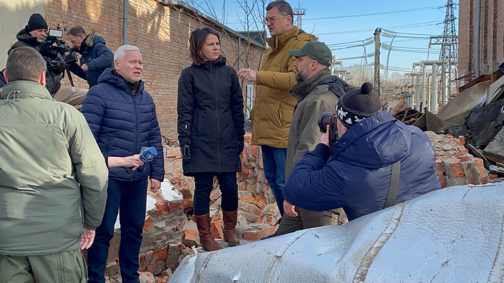 Foreign Minister Annalena Baerbock stands next to Ukrainian Foreign Minister Dmytro Kuleba (3rd from right), Kharkiv Governor Oleh Synehubov (2nd from right) and Kharkiv Mayor Ihor Terekhov (5th from right) in Kharkiv on the site of a substation destroyed by the Russians during her trip to eastern Ukraine.