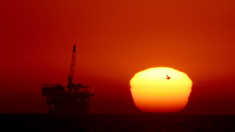 Solen går ned bak en oljeboreplattform utenfor kysten av Huntington Beach mandag 5. september 2022.