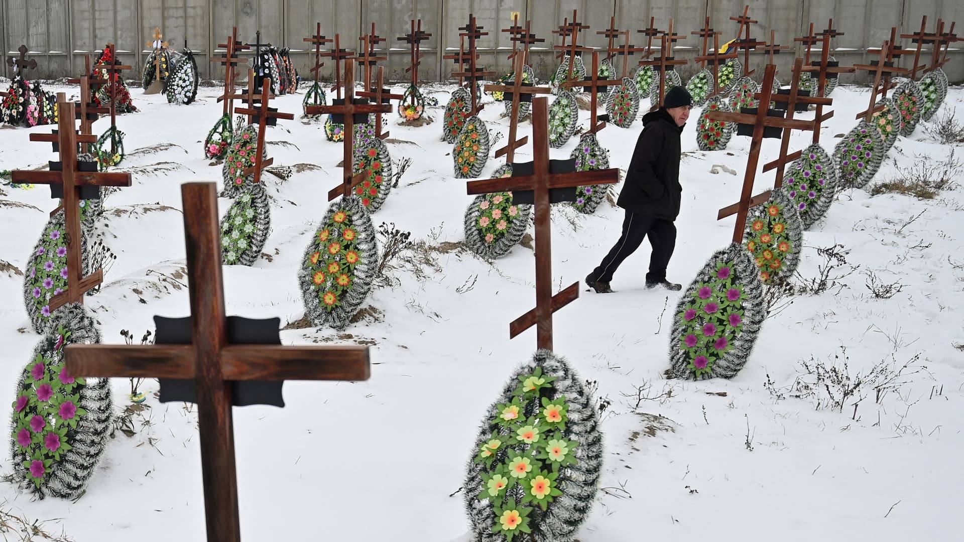 An elderly man walks among the graves of unidentified people, killed during Russian occupation, who were reburied from a mass grave in the small Ukrainian town of Bucha, near Kyiv, on January 12, 2023.