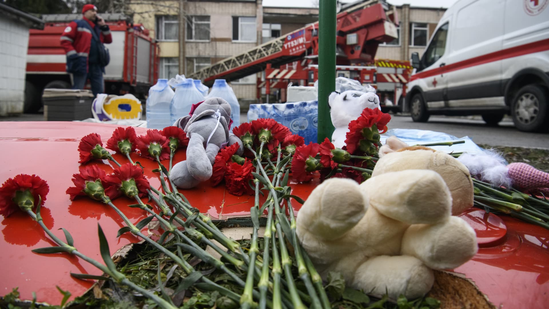 People leave flowers and toys on a fragment of a helicopter that crashed near a kindergarten, in Brovary in the outskirts of Kyiv, Ukraine, on Jan. 18, 2023.