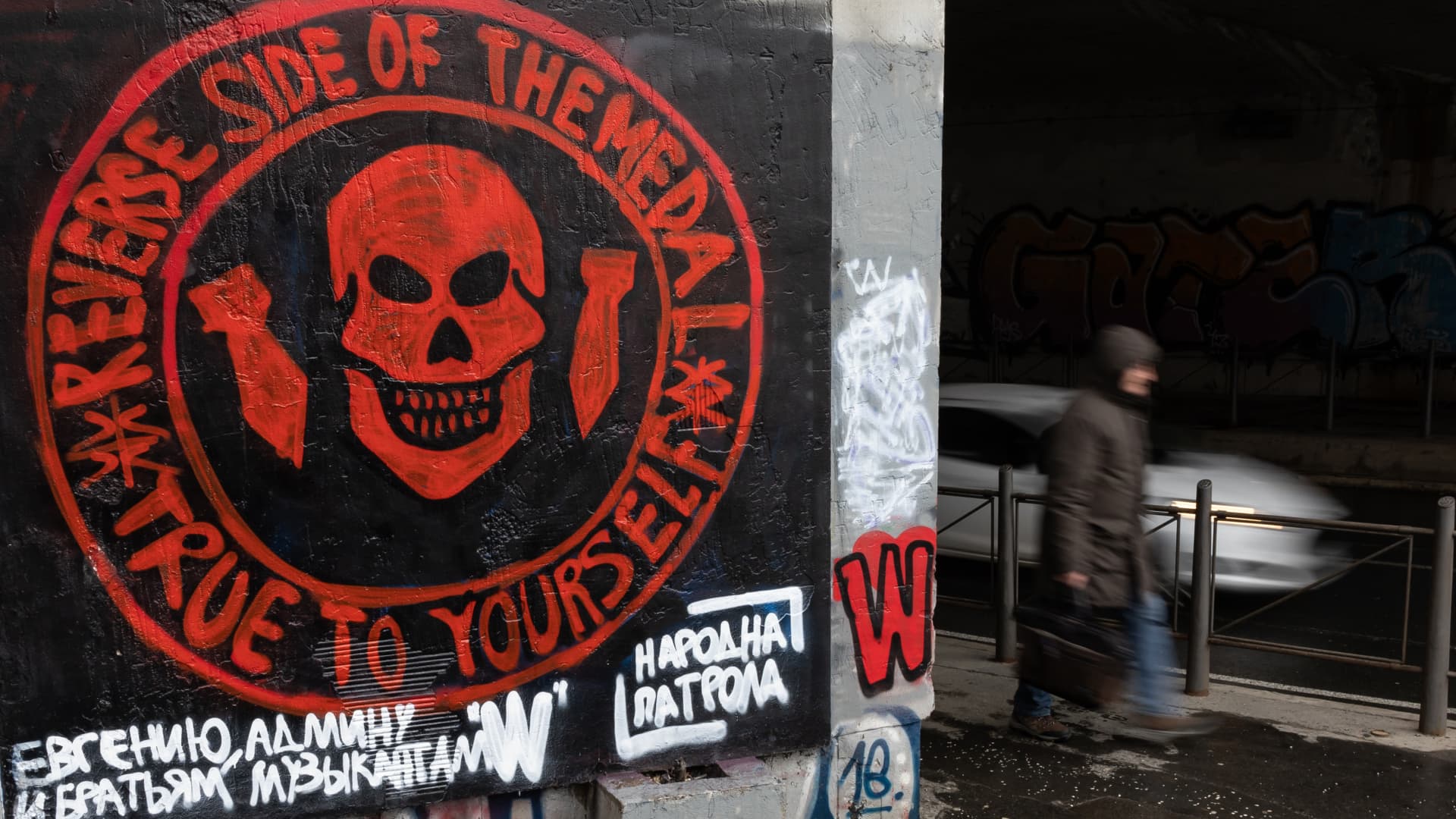 A pedestrian walks past a mural depicting the logo of the Russian mercenary 'Group Wagner' and a slogan in Russian by the informal pro-Russia organisation 'Narodna Patrola (lit.: People Patrol), on January 20, 2023 in Belgrade, Serbia.