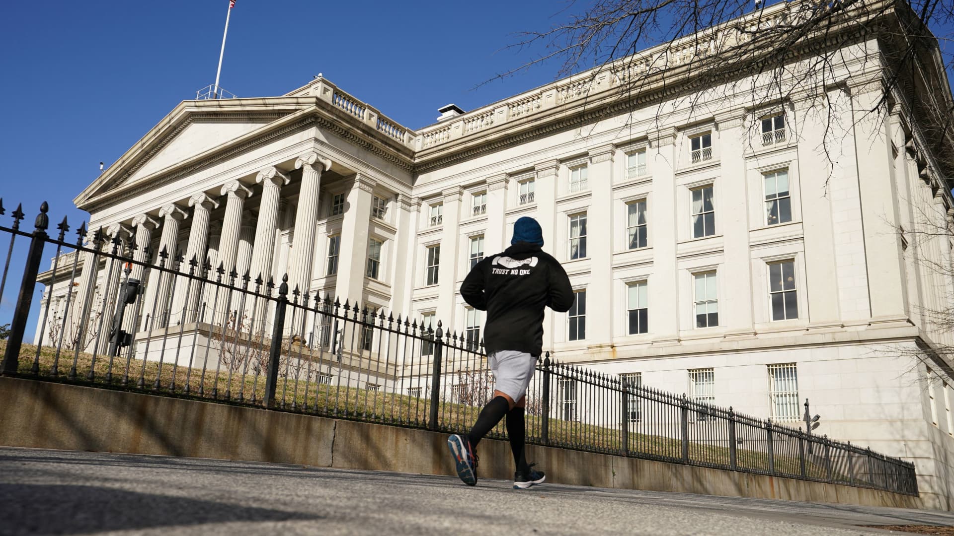 A man jogs past the U.S. Treasury building in Washington, January 20, 2023.
