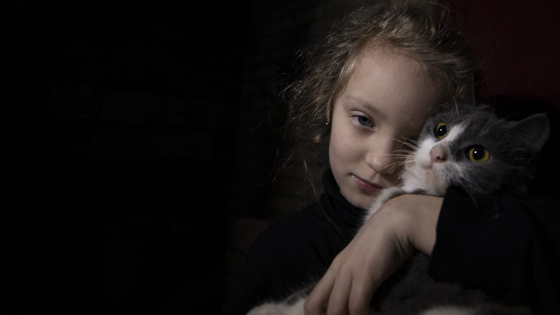 DONETSK OBLAST, UKRAINE - JANUARY 25: Anya, 7, hugs her cat in the shelter where she lives with her family amid the war in Donetsk Oblast, Ukraine on January 25, 2023. (Photo by Mustafa Ciftci/Anadolu Agency via Getty Images)