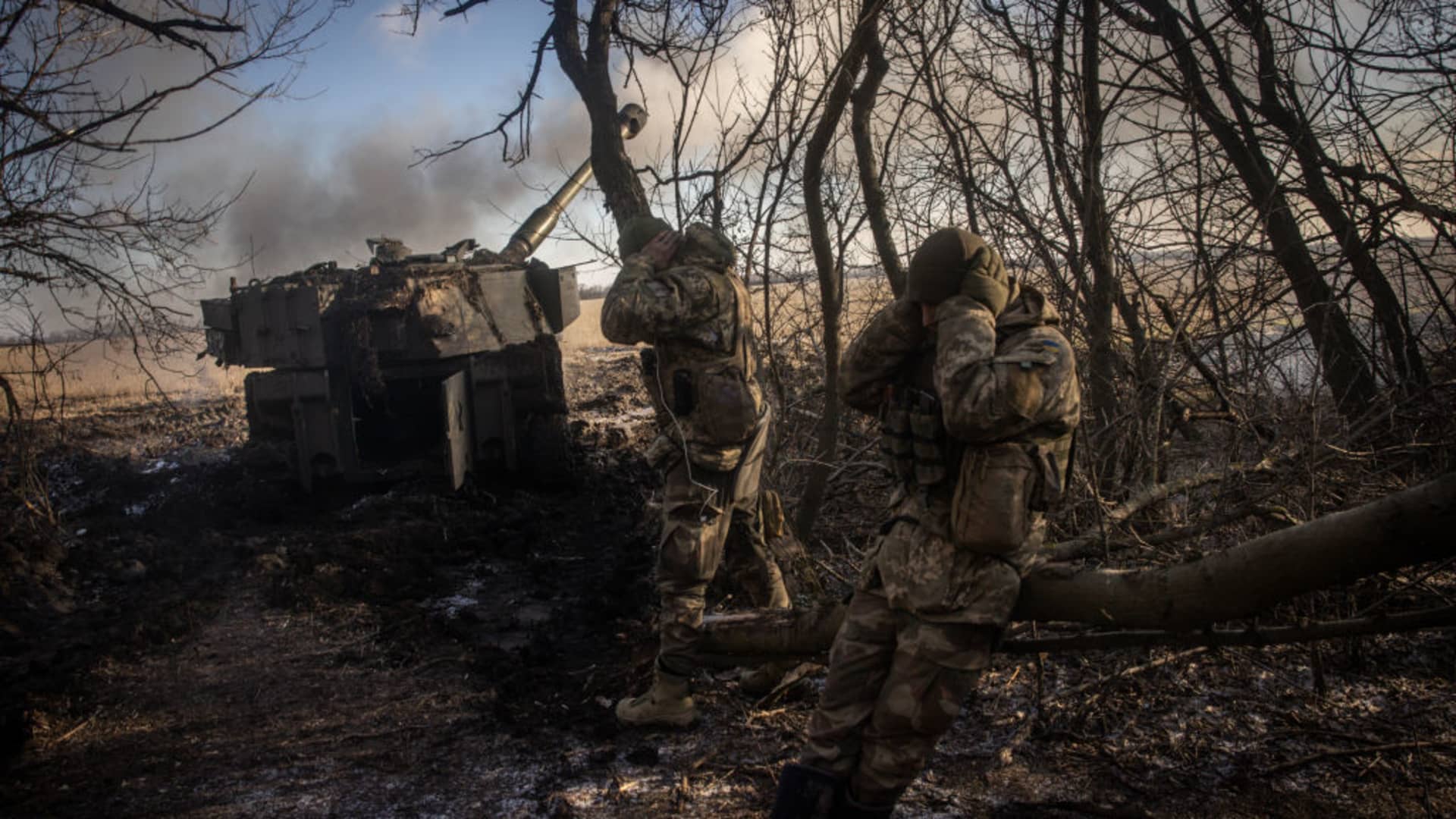 Members of a Ukrainian artillery unit cover their ears as an M109 self-propelled artillery unit is fired at Russian mortar positions around Vuhledar from a front line position on Dec. 19, 2022 in Donetsk, Ukraine.