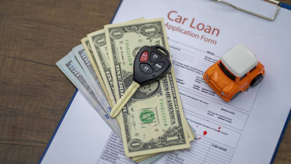 Car key, car toy, and banknote on the car loan contract.