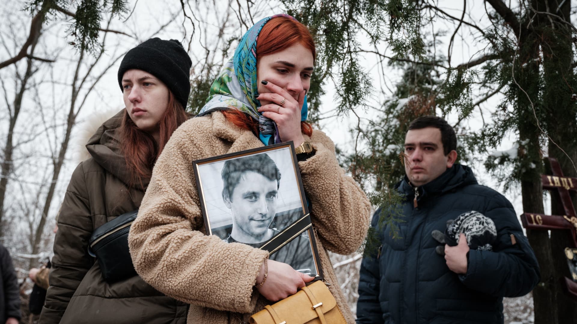 Kateryna Avdeyeva (C), mourns as she holds a portrait of her late friend, Ukrainian serviceman of the Azov battalion killed in action in Bakhmut, 28-year-old orphan Oleksandr Korovniy, as she attends his funeral ceremony at a cemetery in Sloviansk on January 30, 2023, amid the Russian invasion of Ukraine.