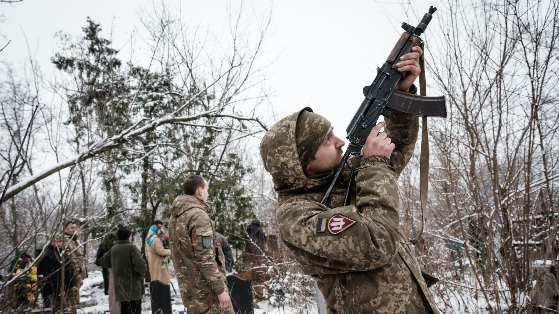 Oleksiy Storozh (R), 28, fires his rifle in the air during the burial of his best friend, the late Ukrainian serviceman of the Azov battalion killed in action in Bakhmut, 28-year-old orphan Oleksandr Korovniy, at a cemetery in Sloviansk on January 30, 2023, amid the Russian invasion of Ukraine. 