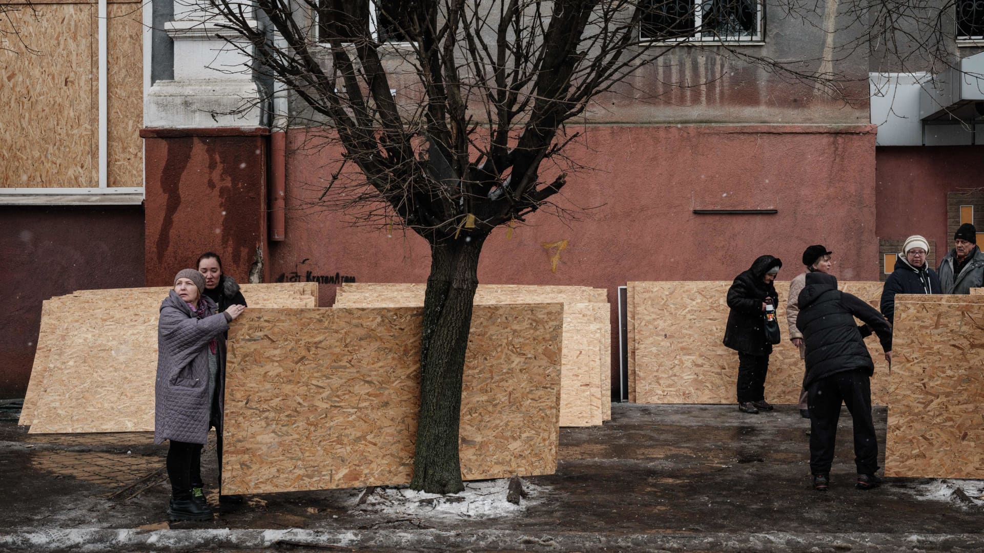 People receive plywood to close broken windows after a rocket strike hit a residential building in Kramatorsk on February 2, 2023, amid the Russian invasion of Ukraine. - At least three people were killed on February 2, 2023, and 20 wounded when a Russian rocket struck a residential building in the centre of Kramatorsk, located in Ukraine's eastern industrial region of Donetsk.