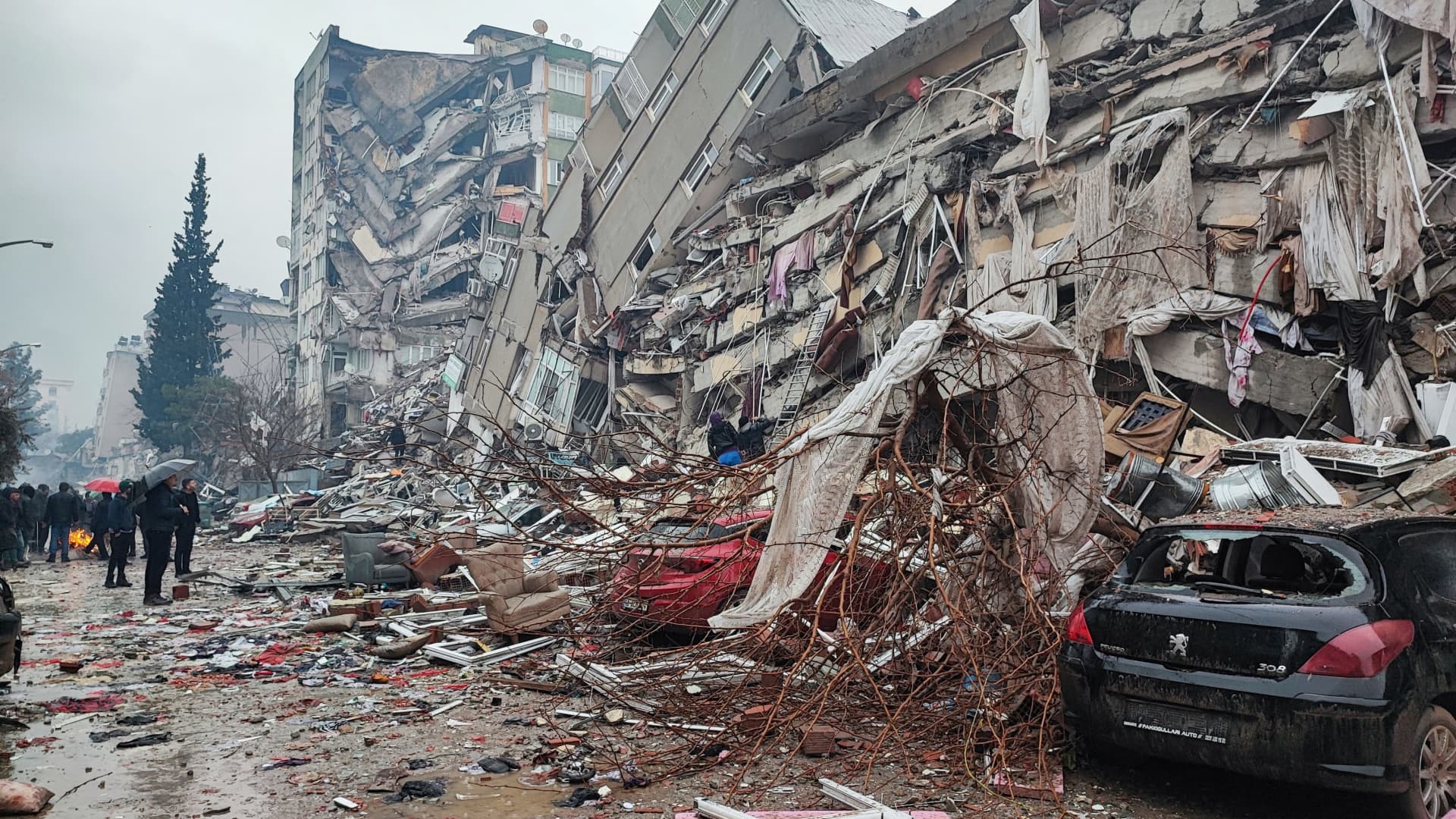 People stand in front of collapsed buildings following an earthquake in Kahramanmaras, Turkey February 6, 2023. 