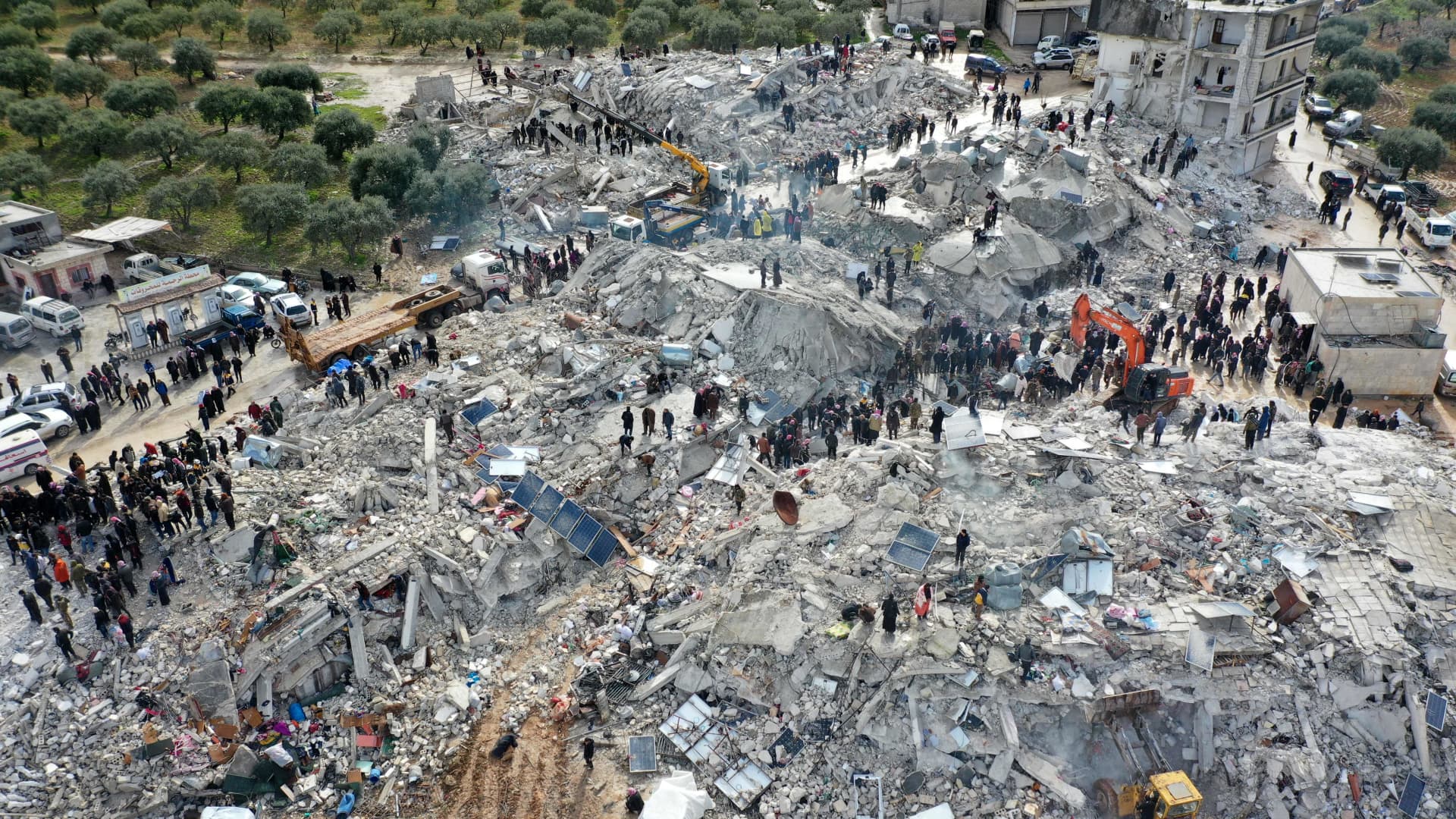 This aerial view shows residents searching for victims and survivors amidst the rubble of collapsed buildings following an earthquake in the village of Besnia near the twon of Harim, in Syria's rebel-held noryhwestern Idlib province on the border with Turkey, on February 6, 2022.