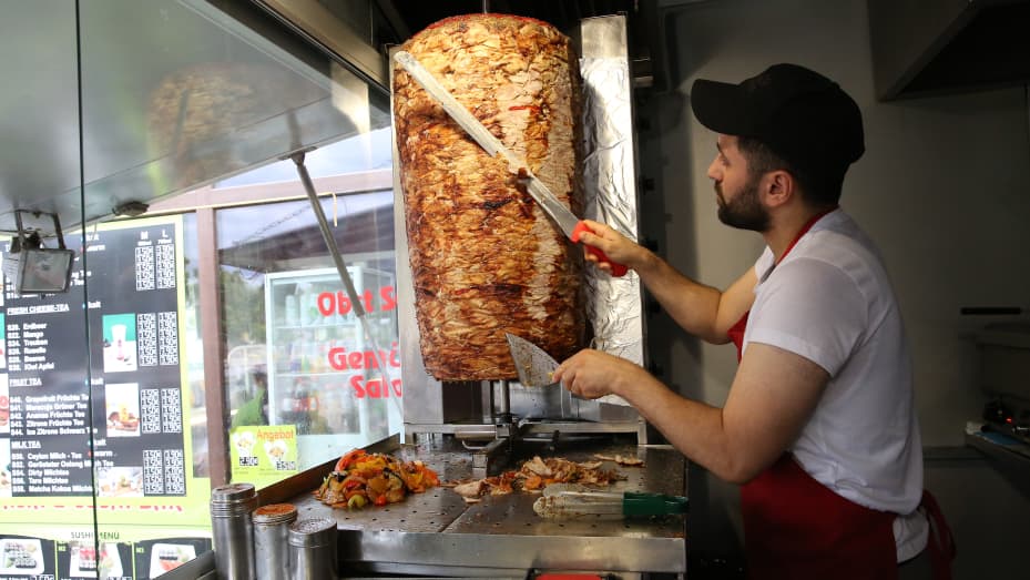 BERLIN, GERMANY - JULY 06: An employee prepares a customer's order at Mustafas Gemüse Kebap on July 06, 2022 in Berlin, Germany. The döner kebab, a fast food sandwich made of stacked, seasoned meat turned on a rotisserie, was popularized in Germany in the early 1970s by Turkish guest workers (Gastarbeiter in German, or migrants arriving in Germany after World War II to counter labor shortages), with more stands offering the dish in Berlin than in Istanbul, and many considering it to be Germany's national