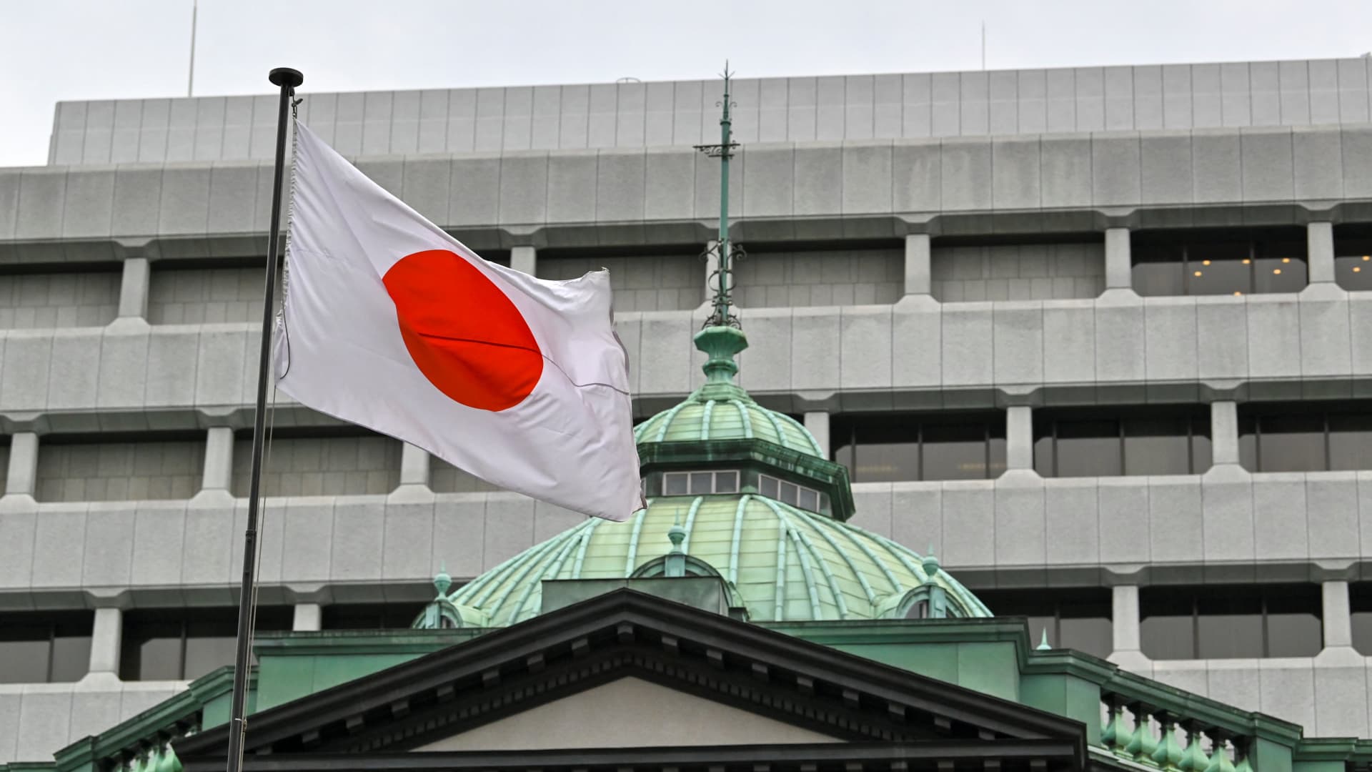 The Japanese flag flutters over the Bank of Japan (BoJ) head office building (bottom) in Tokyo on April 27, 2022.