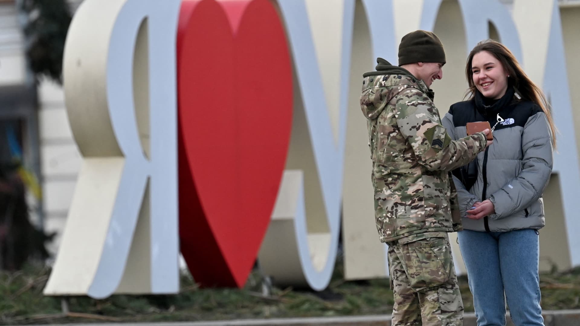 A couple talks as they stand close to a sign that reads, 'I love Ukraine' located at Independence Square in the Ukrainian capital of Kyiv , on Valentine's day, February 14, 2023. 