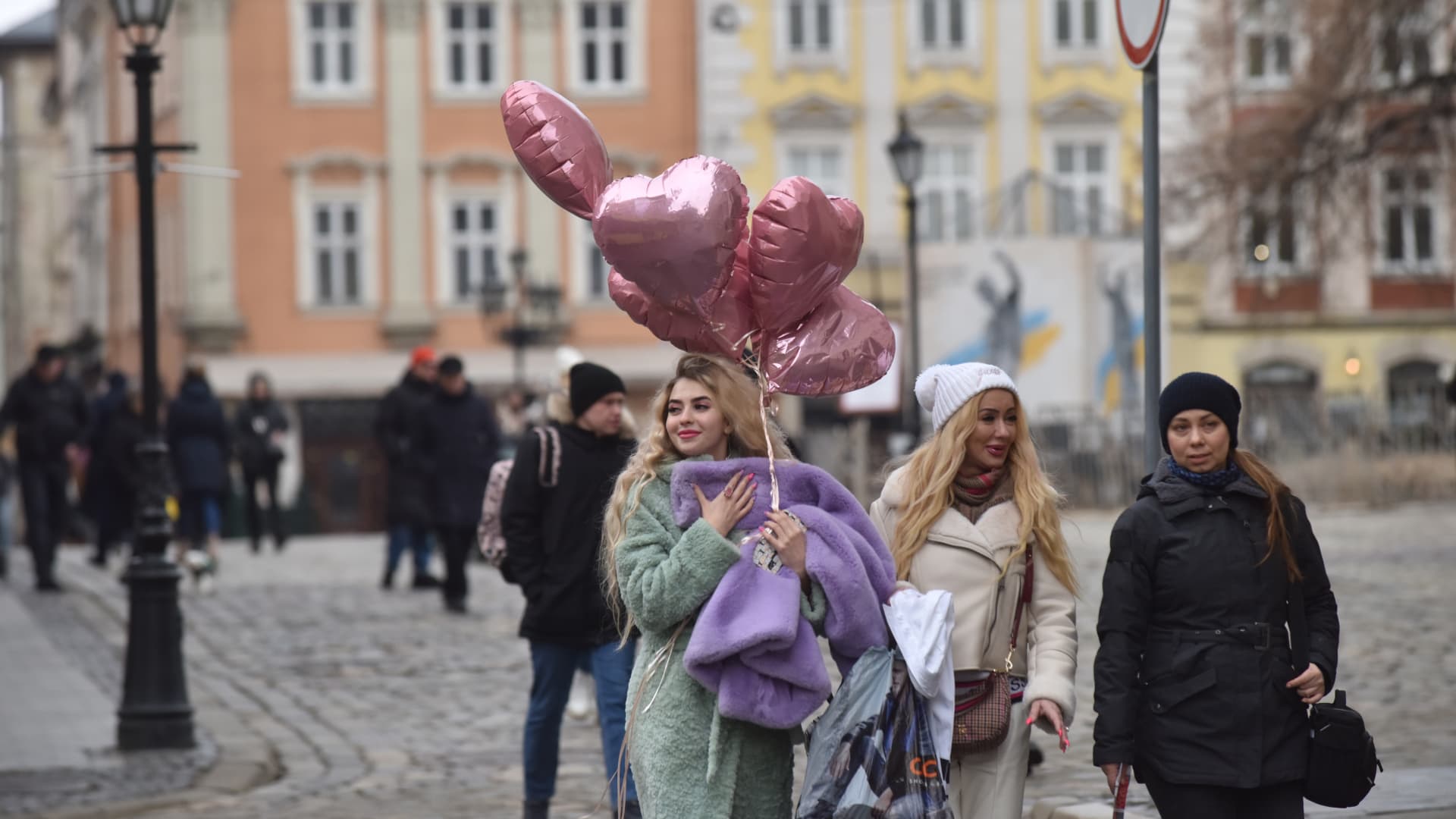 A woman walks with heart-shaped balloons on a city street on Valentine's Day during the Russian-Ukrainian war in Lviv, Ukraine on February 14, 2023. (Photo by Pavlo Palamarchuk/Anadolu Agency via Getty Images)
