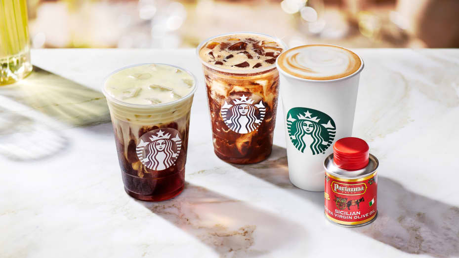A photo showing a small container of Partana olive oil and three drinks: one Golden Foam Cold Brew, one Iced Shaken Espresso and a Caffe Latte.