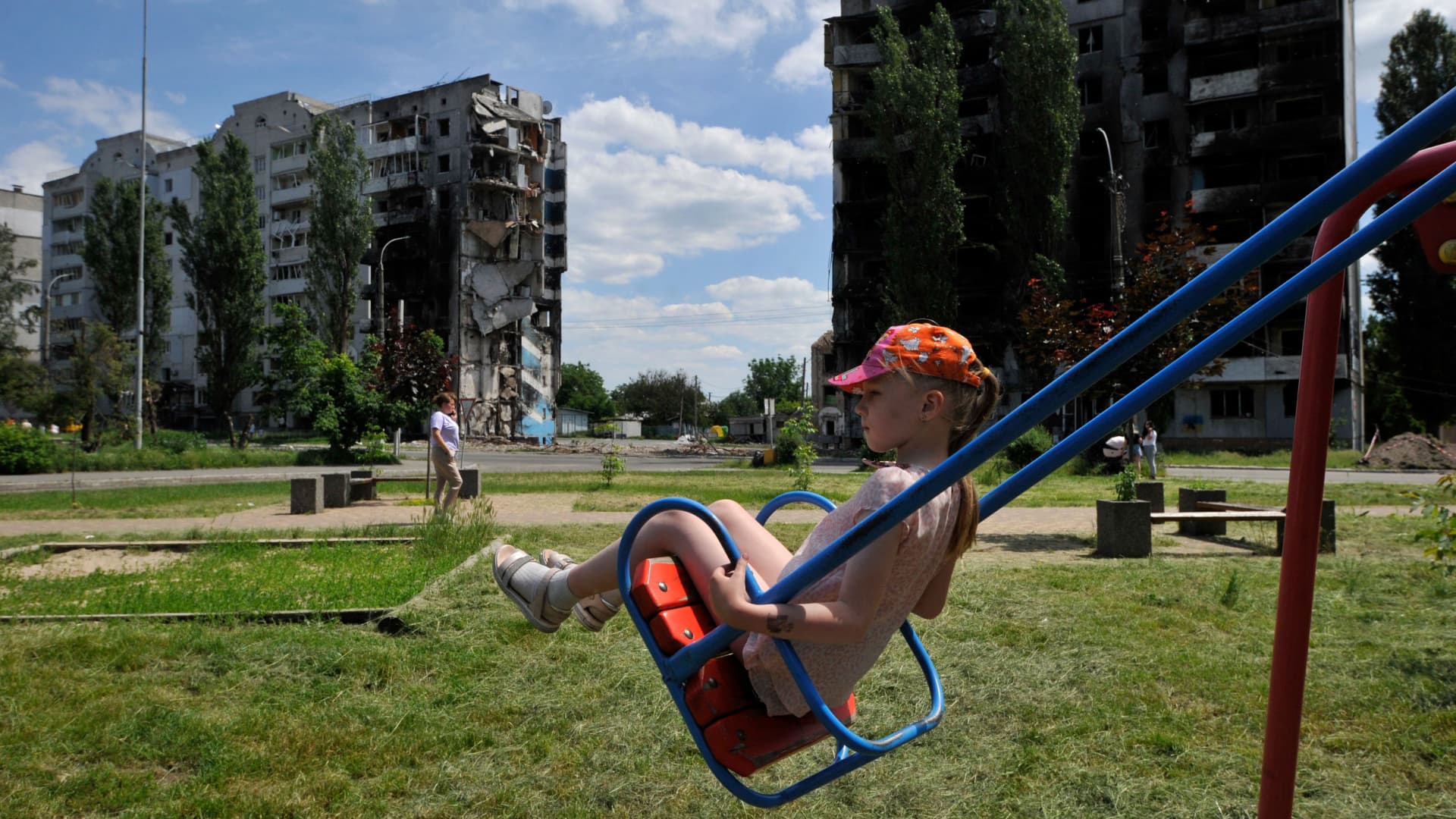 A girl rides a swing on a playground in front of a destroyed residential building in the town of Borodyanka on June 7, 2022, amid the Russian invasion of Ukraine.