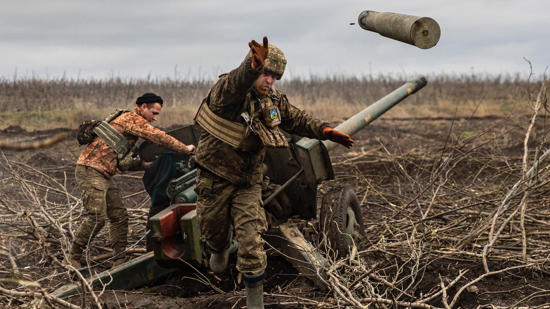 A Ukrainian serviceman of an artillery unit throws an empty shell as soldiers fire toward Russian positions on the outskirts of Bakhmut, in eastern Ukraine, on Dec. 30, 2022.