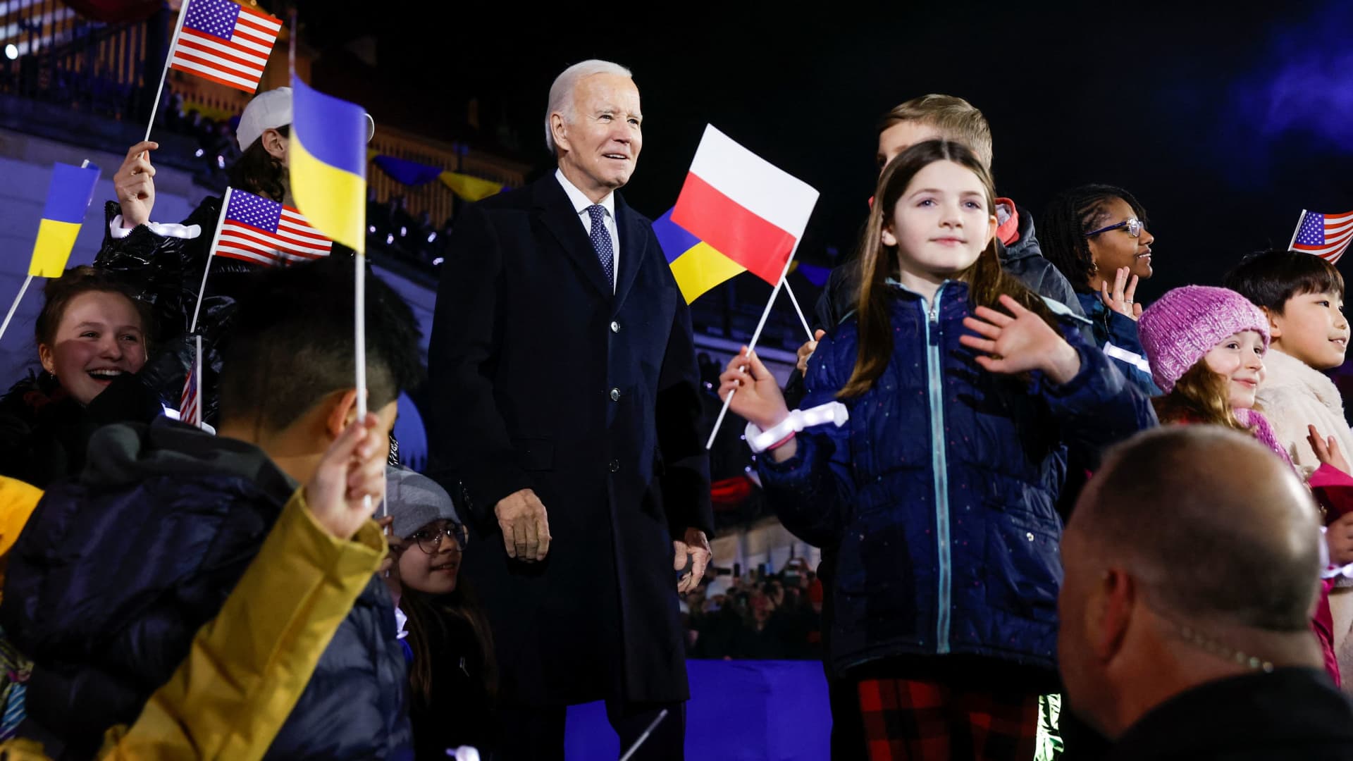 U.S. President Joe Biden stands onstage with children waving flags after he delivered remarks ahead of the one year anniversary of Russia's invasion of Ukraine, outside the Royal Castle, in Warsaw, Poland, February 21, 2023.